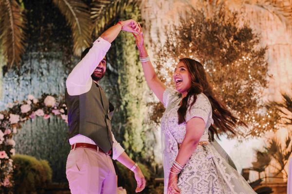 A couple dances joyfully in elegant traditional attire at a festive outdoor event.