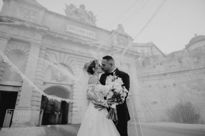 Bride and groom kissing outside historic Victoria Gate, Valletta