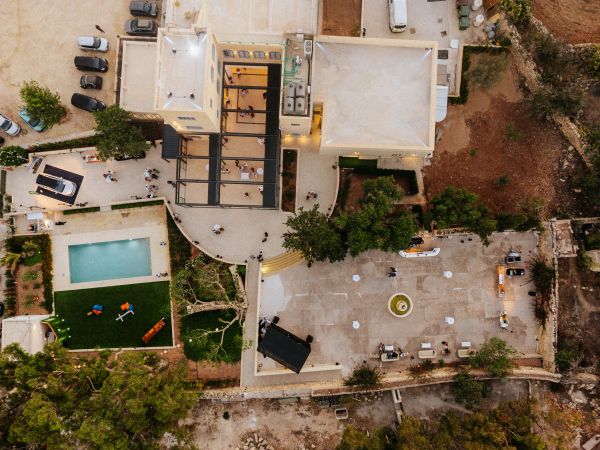 Aerial view of a villa with a swimming pool and outdoor wedding setup