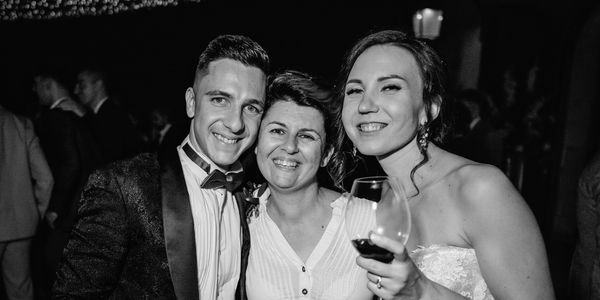 Three people smiling at a formal event, one holding a wine glass.