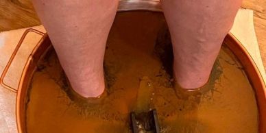 Feet immersed in a reddish-brown mud bath.