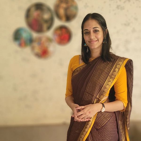 Woman in brown and yellow saree smiling.