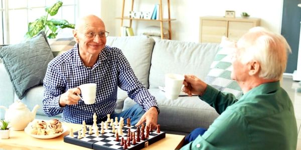 Two elderly men enjoying chess and coffee.