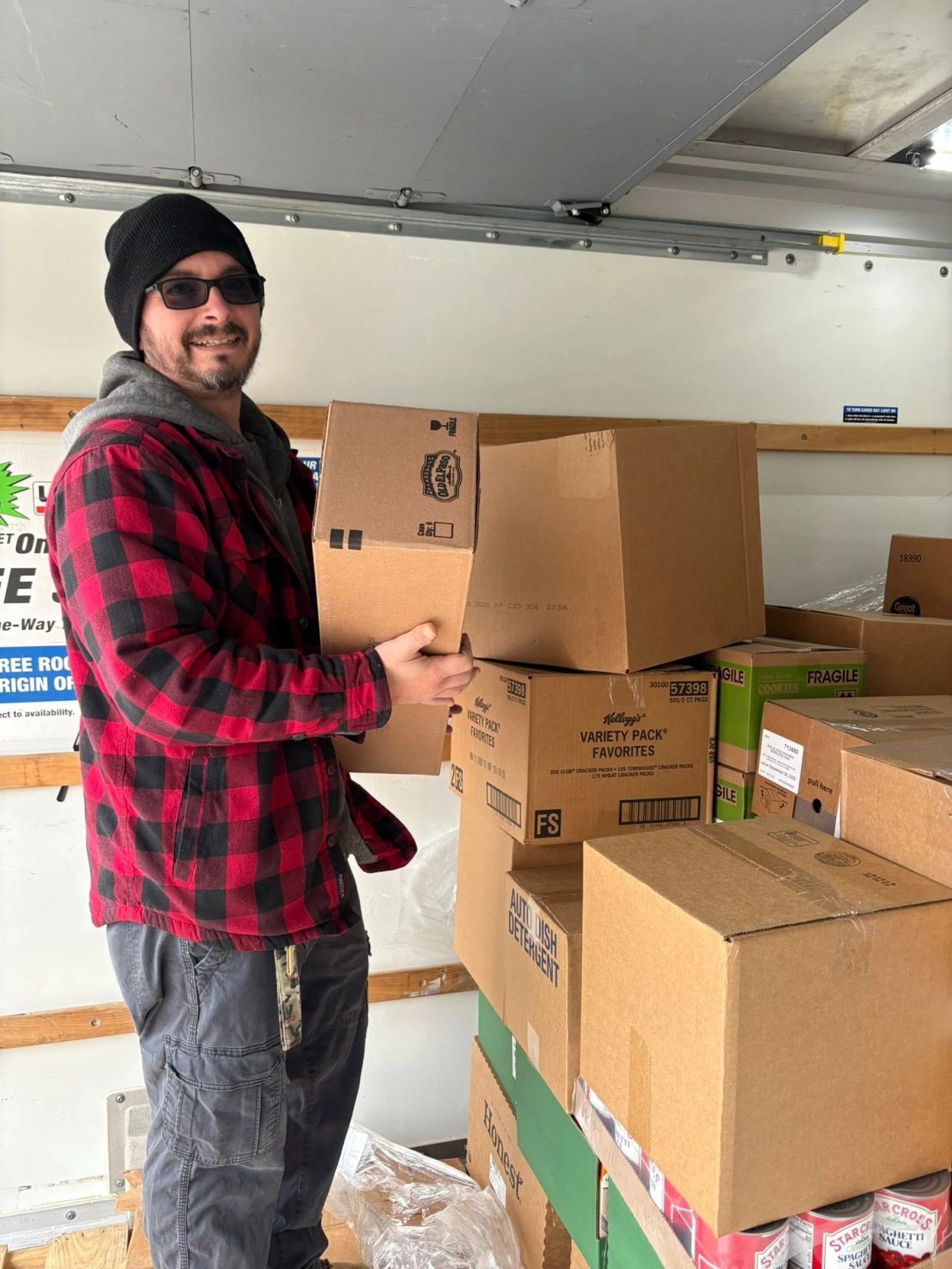 Man holding a cardboard box inside a moving truck.