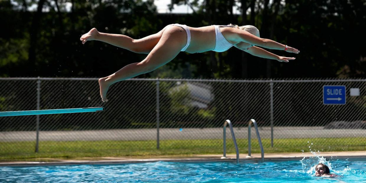 Woman diving into pool from diving board.