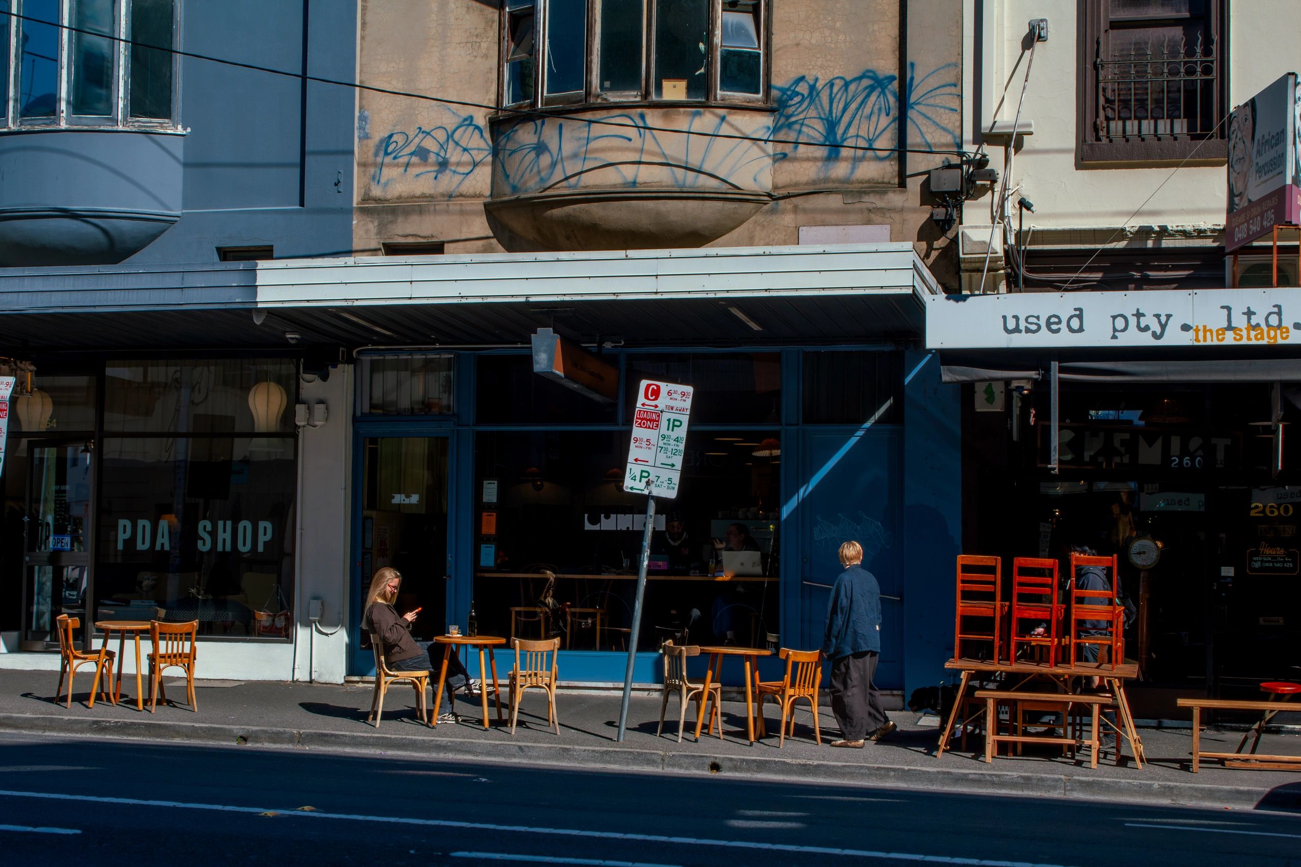 Street scene with outdoor tables and people near shops.