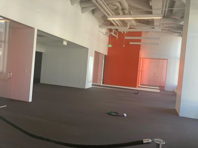 Empty office space with exposed ceiling and orange accent wall.