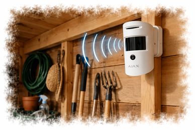 AJAX security sensor mounted on a wooden wall in a garden shed.