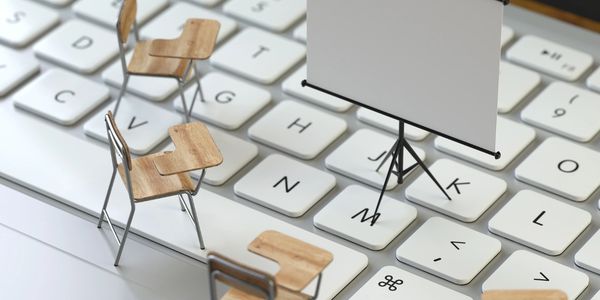 Miniature classroom setup on a computer keyboard with chairs and a projector screen.