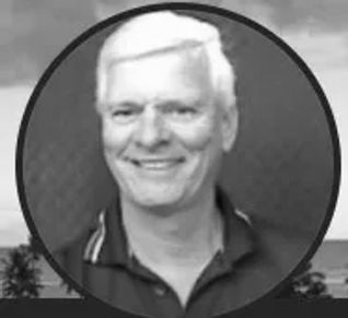 Black-and-white portrait of a smiling man with white hair.