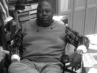 Man sitting at a cluttered desk in an office.