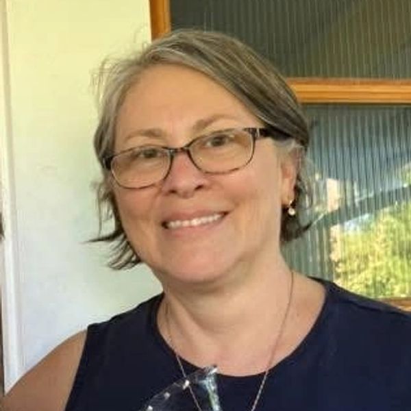 Smiling woman with glasses and short hair.