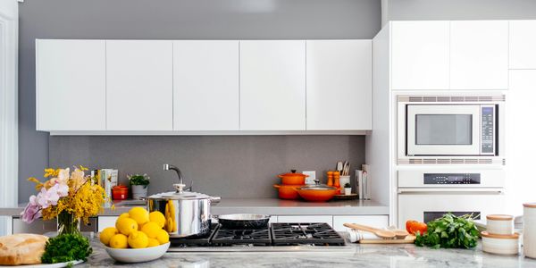 Modern kitchen with white cabinets, marble countertop, and fresh ingredients.