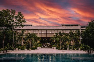 Resort-style swimming pool at sunset surrounded by tropical landscaping at AWA Playacar in Playa del