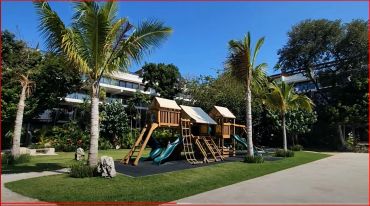 Children's wooden playground set with slides in a park.