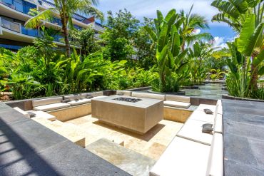 Outdoor seating area with palm trees and fire pit.