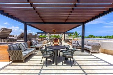 Rooftop terrace with shaded pergola, outdoor dining, and lounge seating at AWA Playacar, offering el