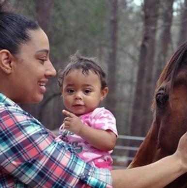 Mother & child petting a horse in the woods.