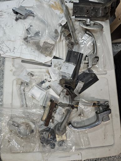 Various metal door handles and hardware parts scattered on a surface.