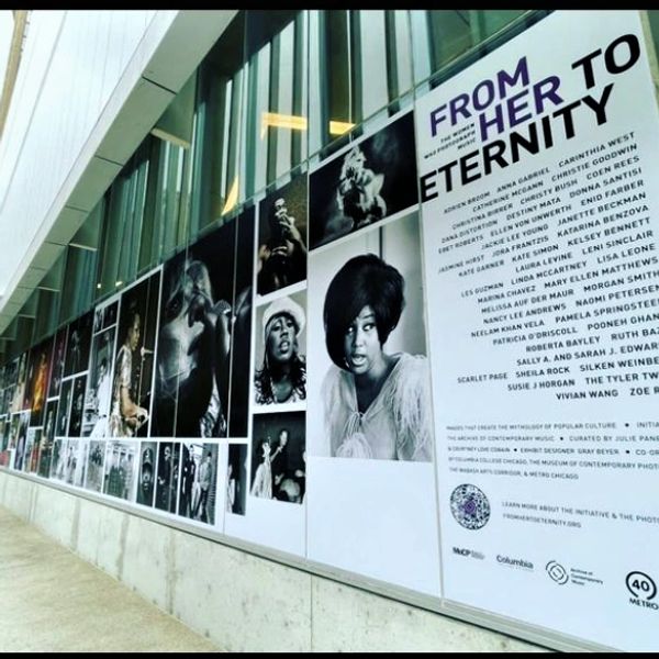 Outdoor photo exhibit titled "From Her to Eternity" showcasing black-and-white portraits of women.