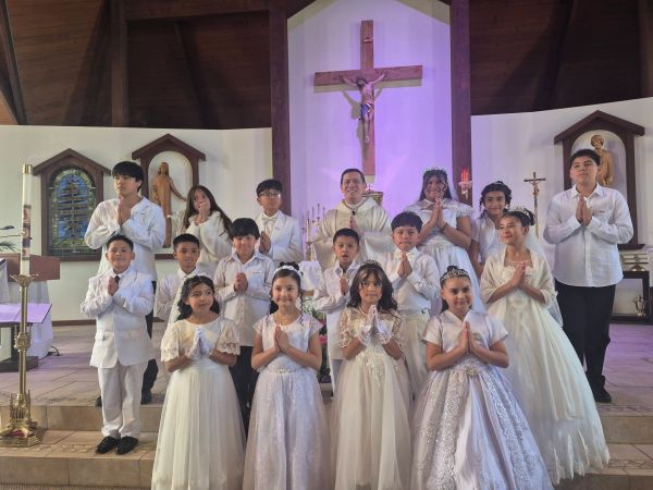 Group of children and a priest in a church.