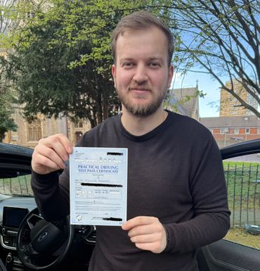 Young man proudly holding a practical driving test pass certificate.
