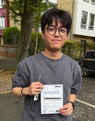 Young man proudly holding his practical driving test pass certificate outdoors.