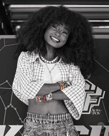 Smiling woman with voluminous hair and stylish accessories poses confidently.