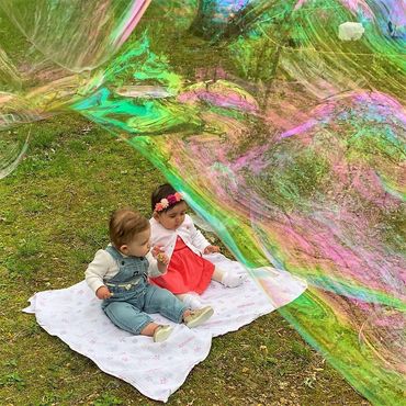 Babies are safe as a giant soap bubble floats gently above. Mom snaps a photo for Grandpop Bubbles.