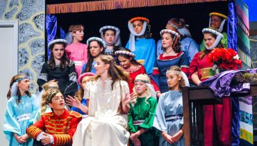 Group of young actors in medieval costumes on stage.