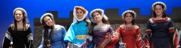 Women dressed in medieval-style gowns on stage.