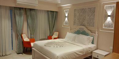 Cozy bedroom with white bed and orange chairs near window.