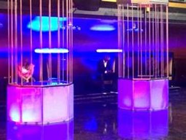 Two illuminated single Go Go Cages on a stage.