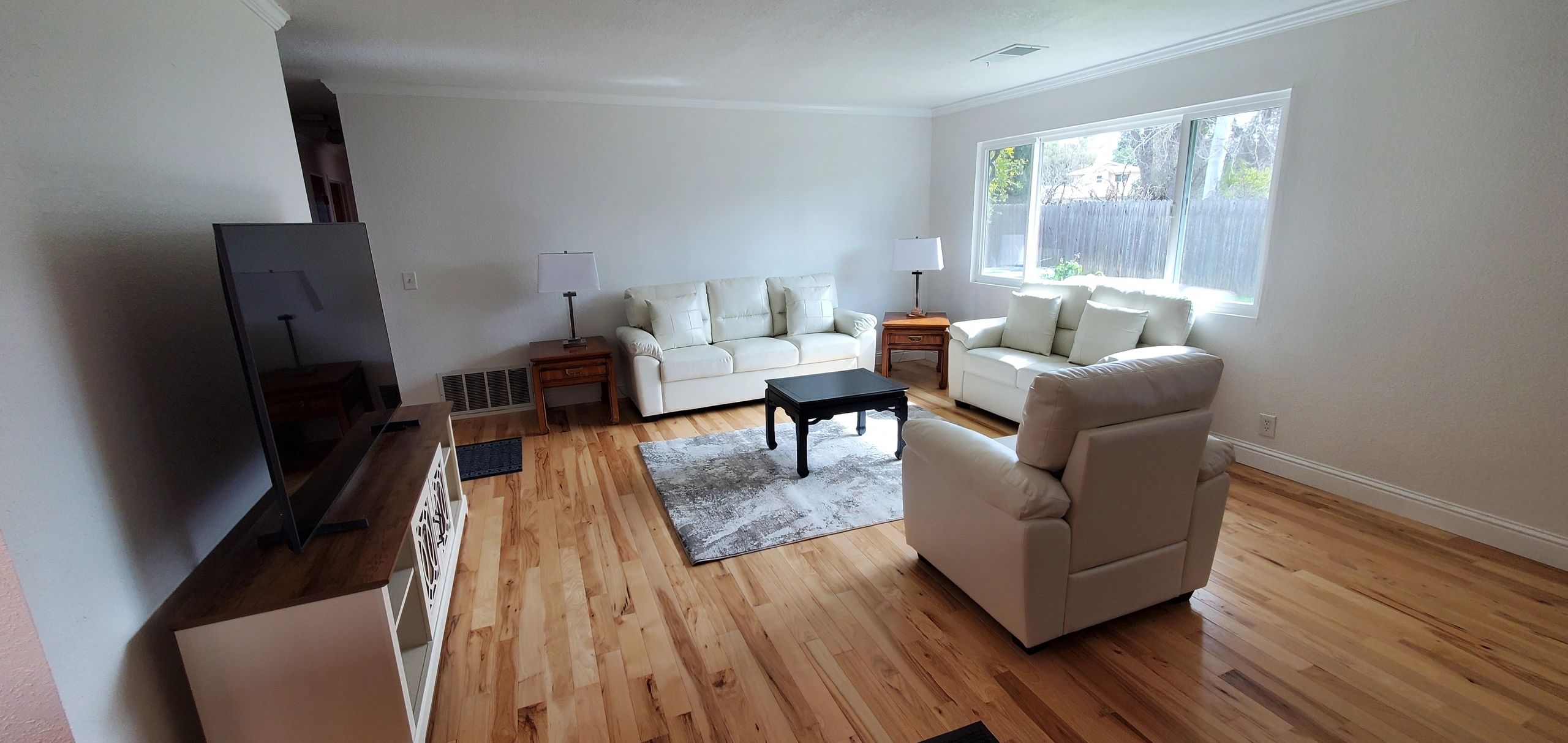 Bright living room with white couches and wooden floors.