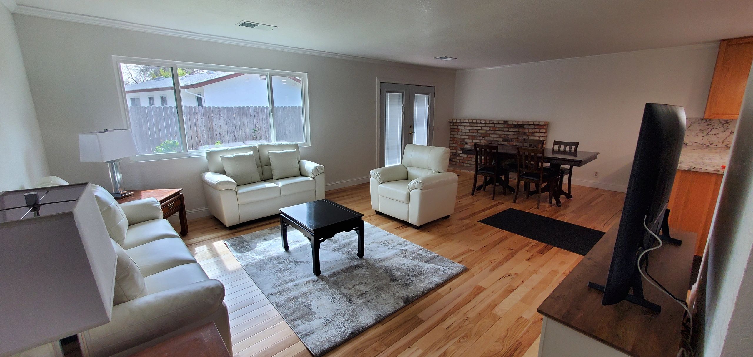 Bright living room with white leather sofas and wooden floor.