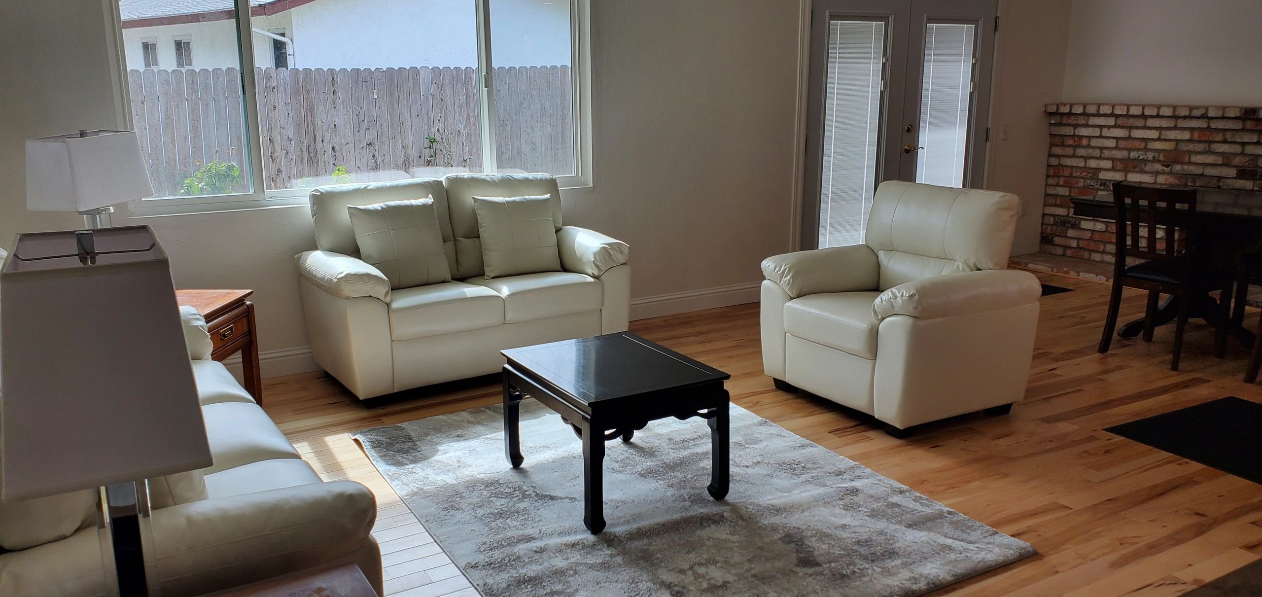 Cozy living room with cream leather sofas, wooden flooring, and a black coffee table.