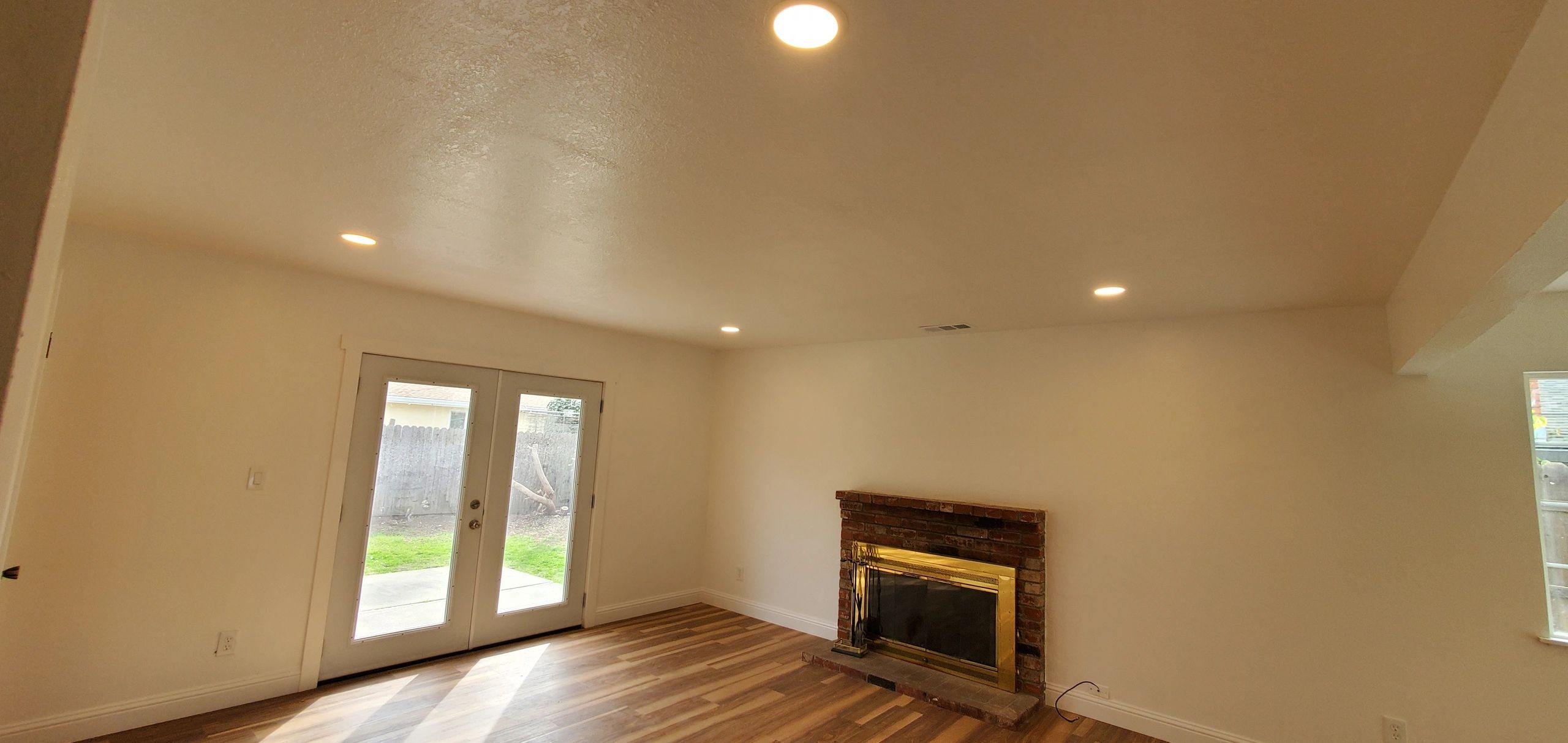 Bright living room with wood flooring and brick fireplace.