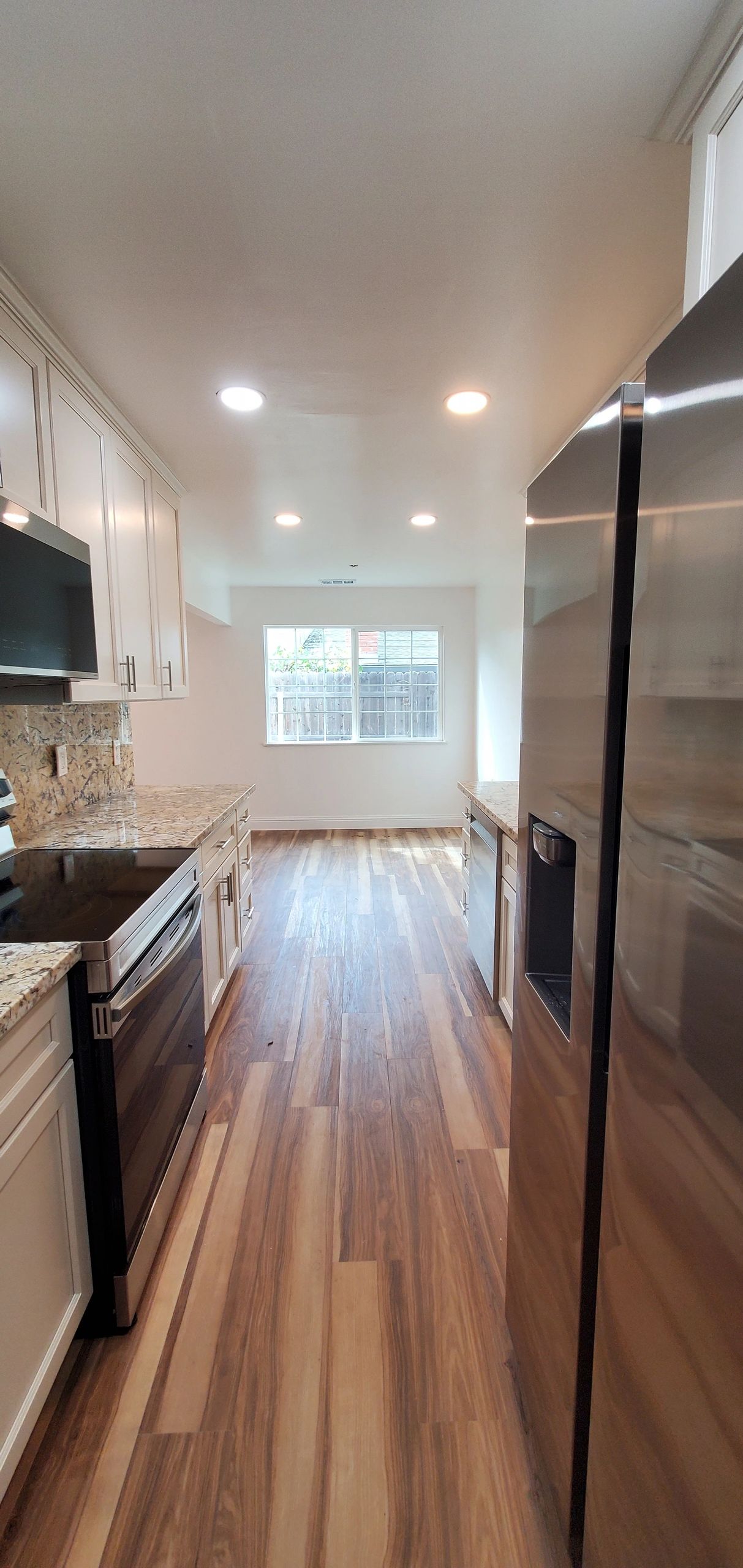 Modern kitchen with wooden floors and stainless steel appliances.