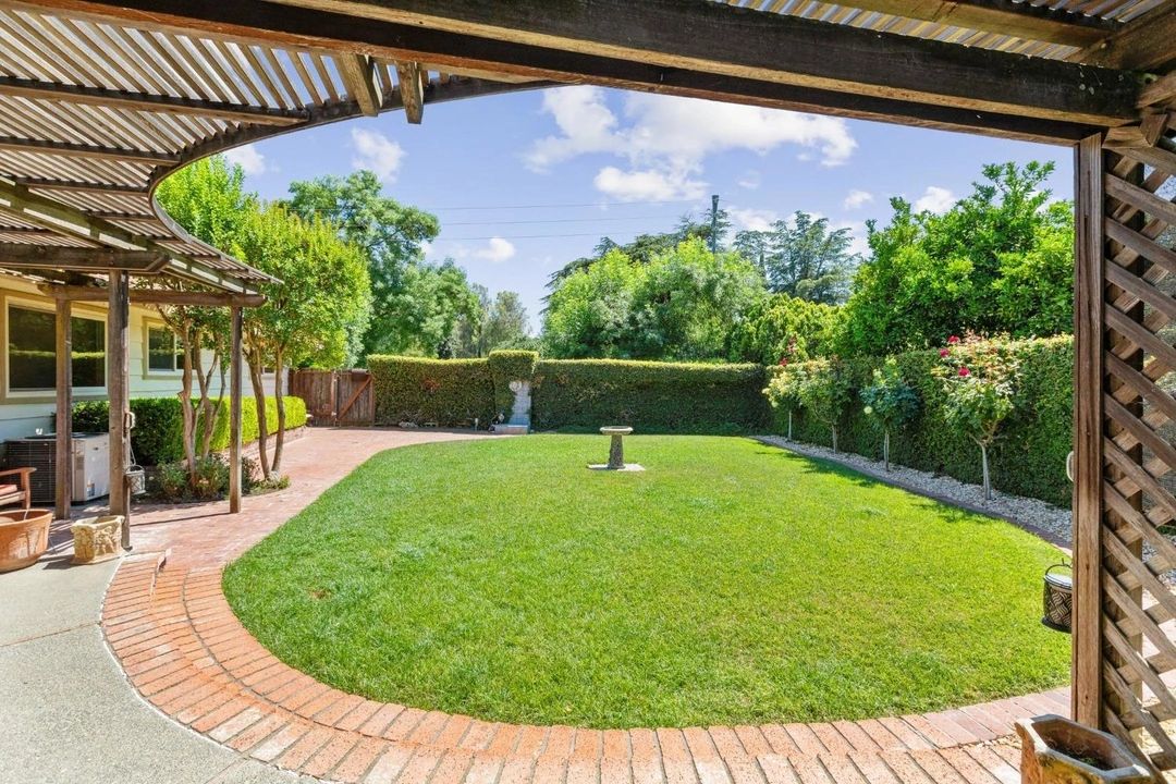 Well-maintained backyard with green lawn and patio under wooden pergola.