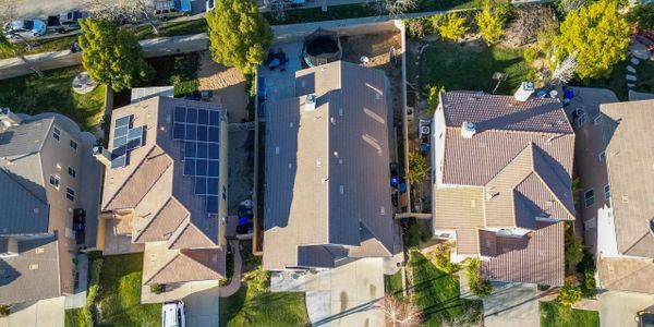 Aerial view of residential houses with solar panels and green yards.