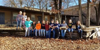 Group of people sitting outside on logs in autumn.