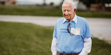 Elderly man wearing a blue shirt outdoors.