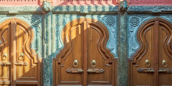 Ornate wooden doors with intricate blue and pink architectural frames.