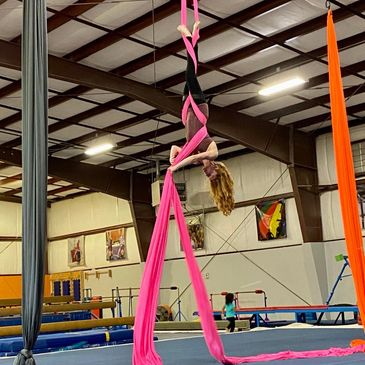 A lady doing aerial silk exercises.