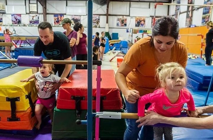 A couple with playing with their tots at the gym.