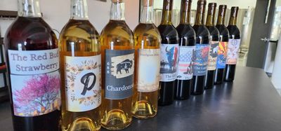 A lineup of various wine bottles with colorful labels on a countertop.