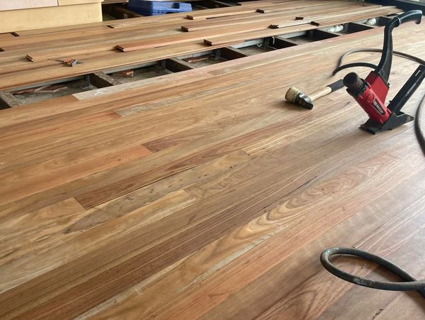 Wooden floor installation in progress with tools and planks scattered.