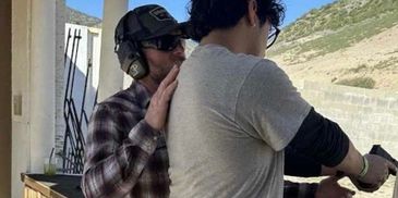 A man instructs another person on shooting at an outdoor firing range.