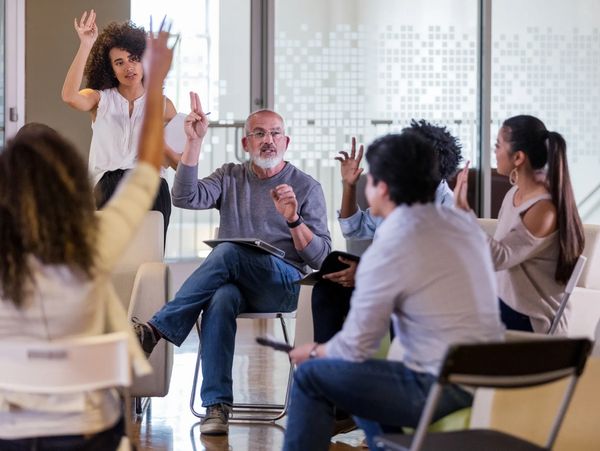 Group of people raising hands in a community meeting discussion