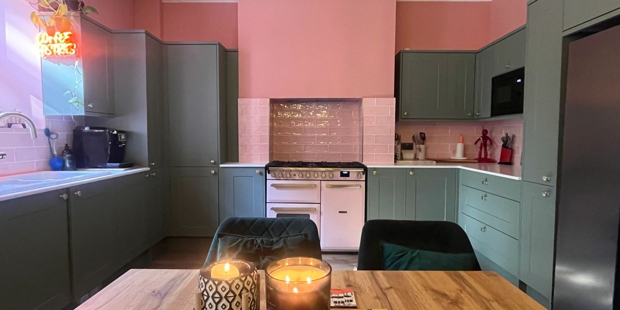 Modern kitchen with teal cabinets and pink walls.